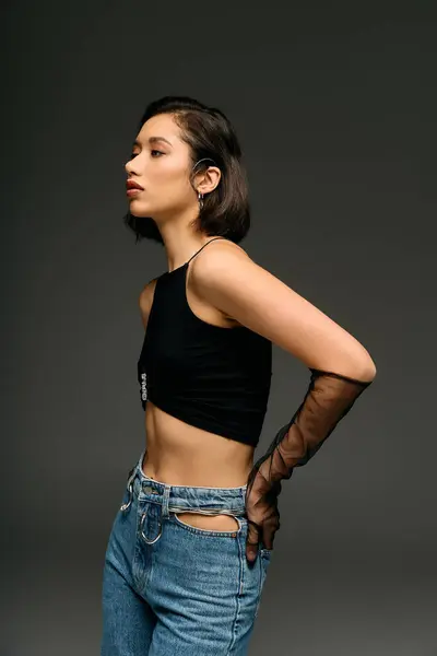 Dans un espace studio, une jeune femme met en valeur sa tenue branchée, rayonnant d'équilibre et d'élégance. — Photo de stock