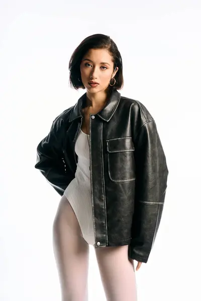 Uma jovem elegante em uma jaqueta preta e bodysuit branco irradia confiança em um estúdio. — Fotografia de Stock
