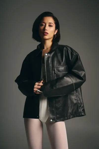 Une jeune femme élégante arbore son look unique avec une veste en cuir audacieuse et de la confiance. — Photo de stock