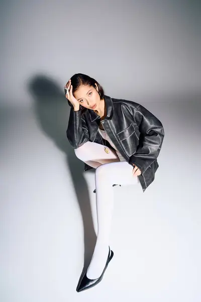 A stylish young woman sits elegantly, radiating confidence and contemporary flair. — Stock Photo