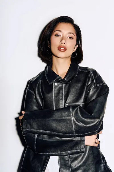 A young woman confidently flaunts her style in an oversized black leather jacket. — Stock Photo
