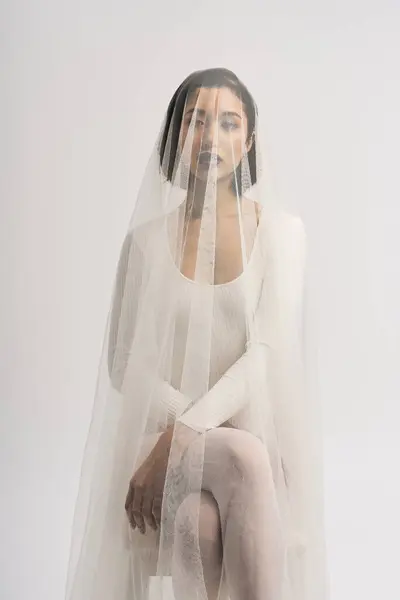 A lovely young bride sits gracefully, her veil draping around her in timeless elegance. — Stock Photo