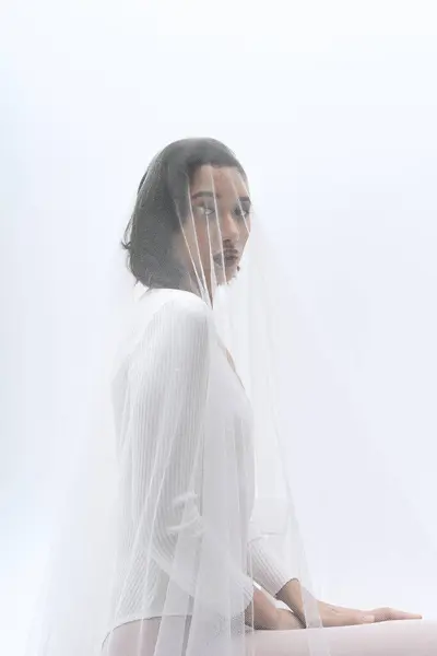 Une jeune mariée s'assoit gracieusement, mettant en valeur sa beauté et son élégance tout en étant ornée d'un voile doux. — Photo de stock