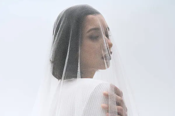 A radiant young bride stands delicately, draped in a fine veil, exuding grace and beauty. — Stock Photo