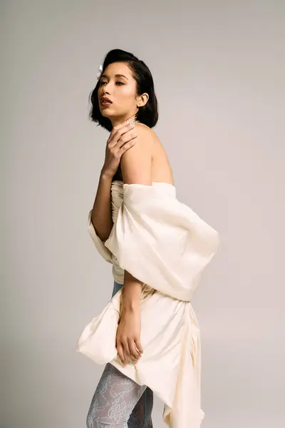 A poised bride displays her stunning gown against a neutral backdrop. — Stock Photo