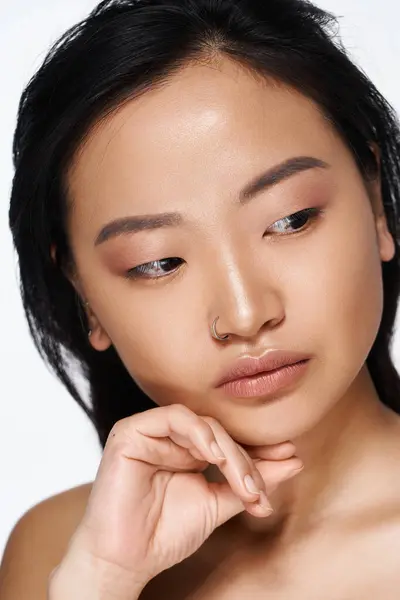 A young Asian woman rests her chin on her hand, lost in thought during a quiet moment. — Stock Photo