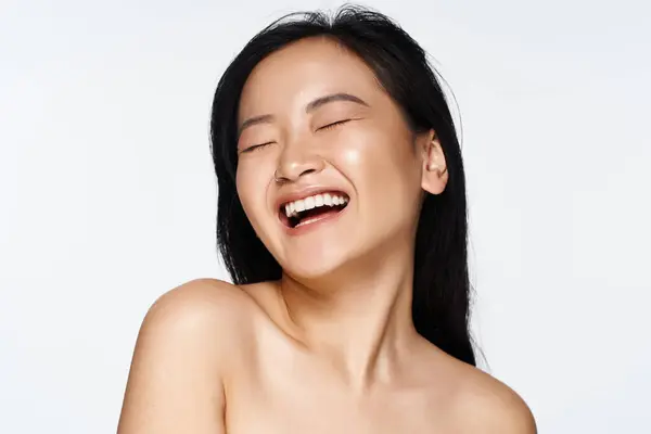 Young woman with long black hair beams brightly, radiating joy and positivity in a vibrant setting. — Stock Photo