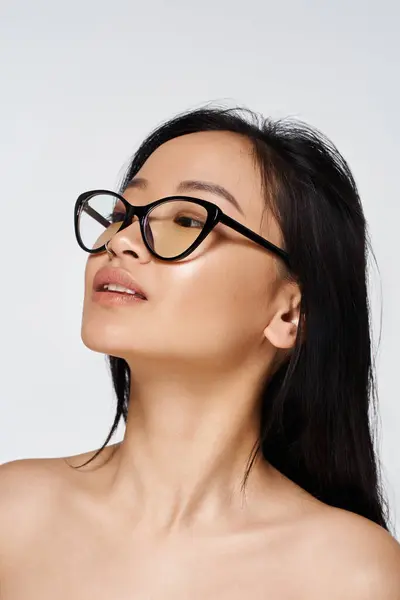 A young Asian woman poses gracefully in trendy glasses, showcasing her elegant features. — Stock Photo