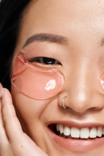 Young asian woman relaxes at home while applying soothing gel eye patches for vibrant skin. — Stock Photo