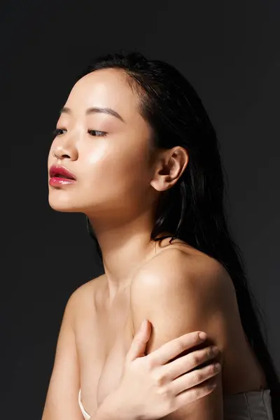 A young asian woman poses elegantly, showcasing her natural beauty and serenity in soft lighting. — Stock Photo