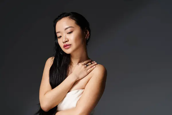 A young Asian woman gracefully poses in a minimalistic studio, showcasing her natural beauty. — Stock Photo