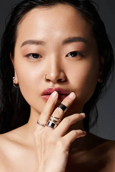 Une jeune femme asiatique confiante affiche sa beauté et ses bijoux uniques dans un cadre moderne. — Photo de stock