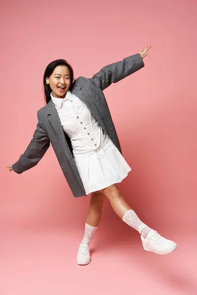 A young woman in a chic outfit smiles joyfully in a vibrant setting. — Stock Photo