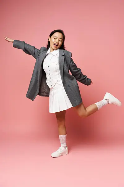 A young asian woman playfully poses with one leg raised, brightening the space with her smile. — Stock Photo