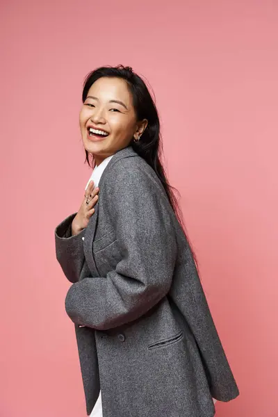 Una hermosa joven asiática emana felicidad mientras posa juguetonamente con una elegante chaqueta. - foto de stock