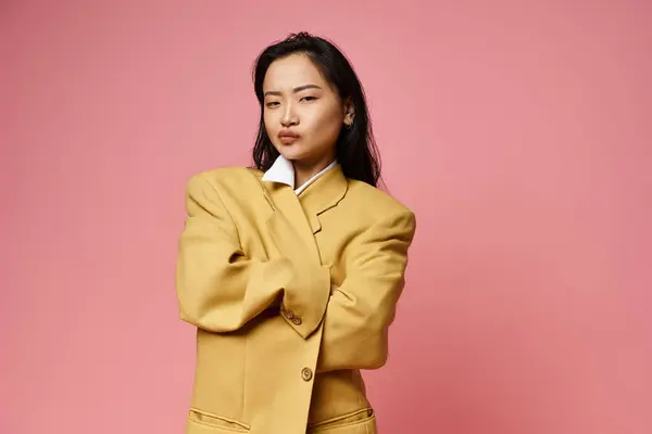 A young Asian woman confidently poses in a stylish oversized jacket with a bold look. — Stock Photo