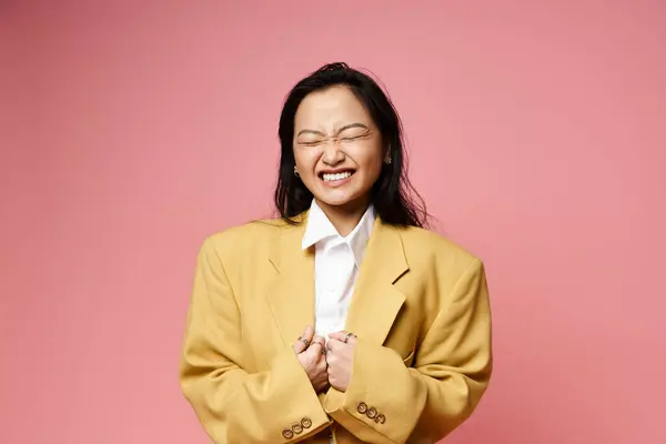 A young Asian woman in a big yellow jacket smiles, reflecting her playful spirit. — Stock Photo