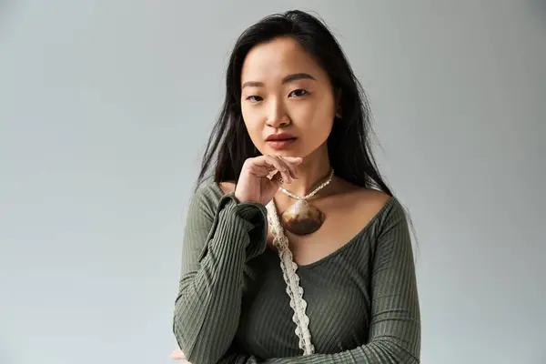 A young Asian woman poses thoughtfully in a minimalist studio, highlighting her style and grace. — Stock Photo