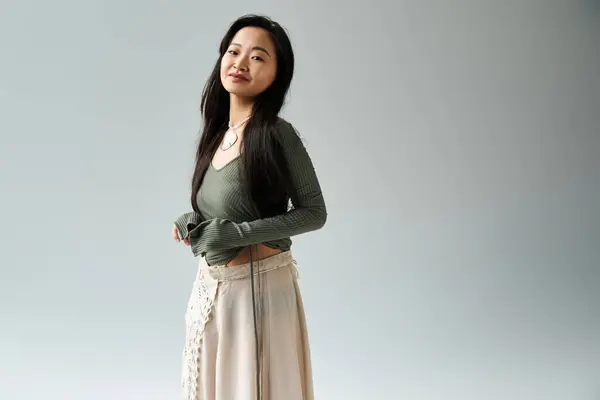 A young Asian woman elegantly displays her outfit in a serene, artistic setting. — Stock Photo