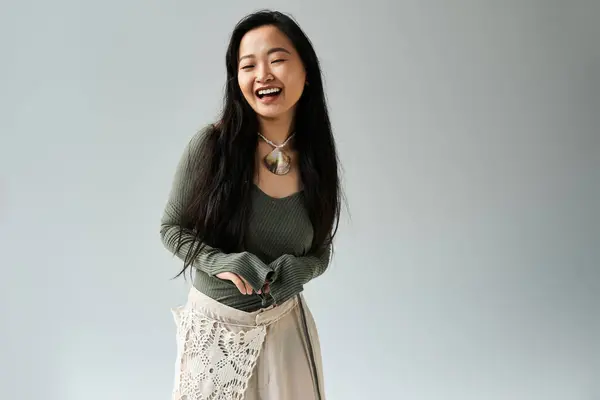 A joyful young Asian woman laughs in a trendy outfit, radiating confidence and elegance. — Stock Photo