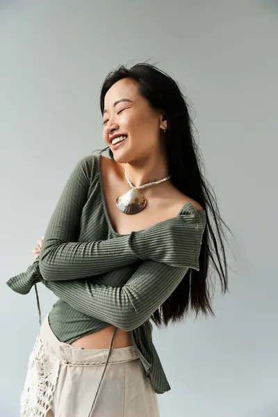 A young asian woman radiates happiness, showcasing her fashion sense with a warm smile indoors. — Stock Photo