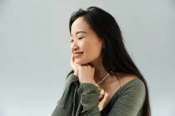 A young woman with lovely features smiles gently, resting her chin on her hand, radiating joy. — Stock Photo