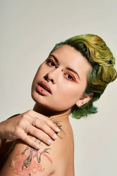 Una mujer vibrante con maquillaje audaz y cabello colorido posa con elegancia, irradiando confianza. - foto de stock