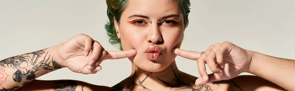 A lively young woman poses playfully, showing off her intricate tattoos and stylish makeup. — Stock Photo