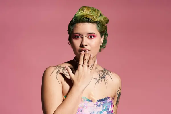 Confident woman poses with unique makeup, vibrant hair, and fashion against a pink backdrop. — Stock Photo