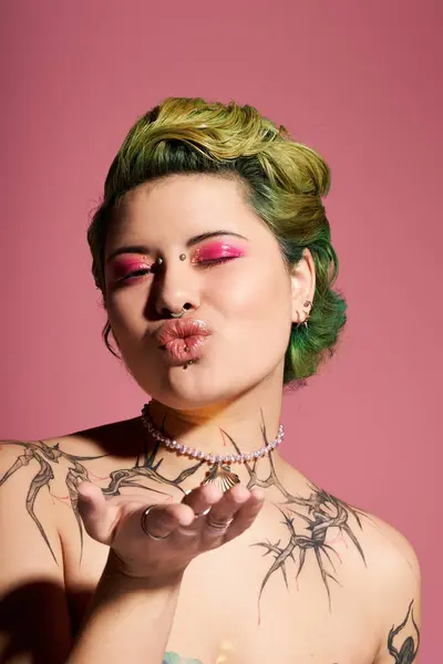 Una giovane donna sicura di sé con i capelli verdi e tatuaggi artistici soffia un bacio. — Foto stock