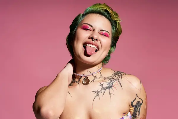 A vibrant young woman shows off her unique fashion and playful spirit against a pink backdrop. — Stock Photo