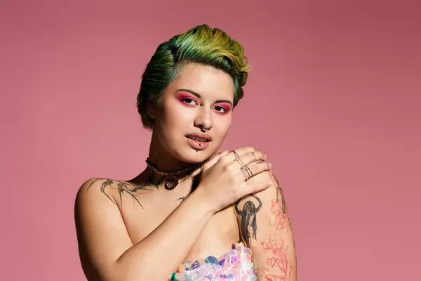 A young woman exudes confidence in vibrant makeup and an artistic outfit against pink. — Stock Photo