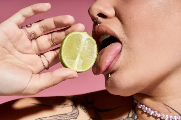 A young woman savors a lime slice, exuding vibrant energy and confidence. — Stock Photo