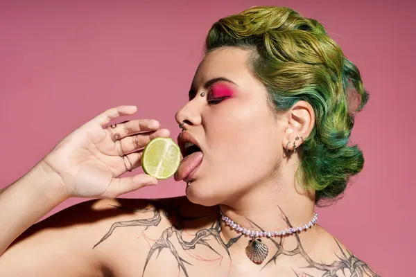 A young woman flaunts her style with colorful makeup, vibrant hair, and a lime. — Stock Photo