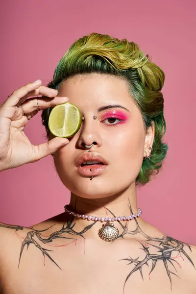 A young woman playfully poses with a lime, showing off her stylish makeup and tattoos. — Stock Photo