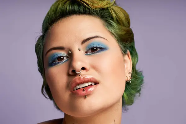 A stunning young woman with green hair and bold makeup poses confidently in vibrant fashion. — Stock Photo