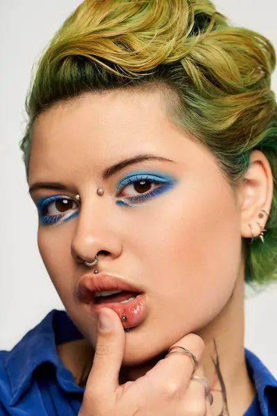 A young woman with vibrant green hair and eye makeup poses confidently, touching her lips. — Stock Photo