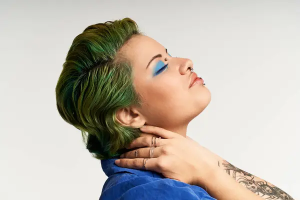 A young woman expresses her individuality with colorful hair and striking makeup, posing elegantly. — Stock Photo