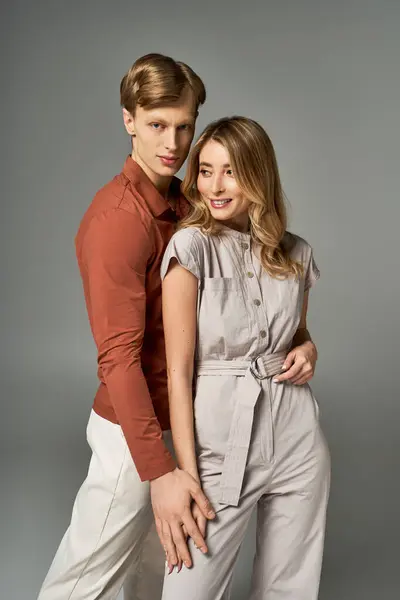 A fashionable young couple poses warmly in a studio, showcasing elegant spring attire. — Stock Photo