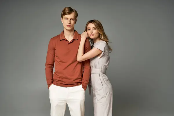 A fashionable young couple showcases vibrant spring outfits while posing closely in a studio. — Stock Photo