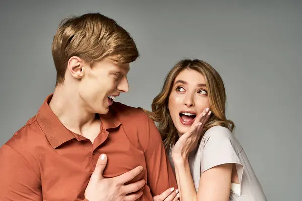 A young couple in trendy spring outfits playfully engages in a lively moment together. — Stock Photo