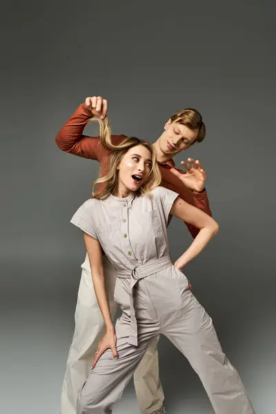 A young couple embraces playful spring fashion, showcasing their stylish outfits with fun poses. — Stock Photo