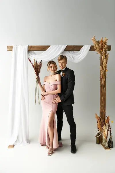 A young couple stands together under a beautiful arch, celebrating their spring wedding in style. — Stock Photo
