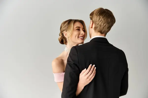 A radiant young couple shares a warm embrace at their spring wedding, smiling happily together. — Stock Photo