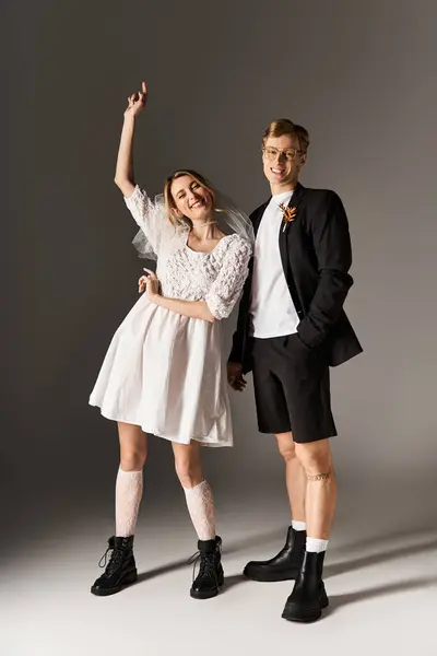 A young couple joyfully poses in stylish wedding attire against a neutral backdrop. — Stock Photo