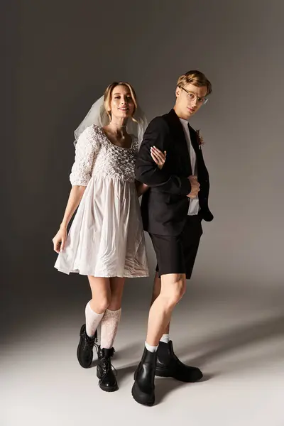 Una alegre pareja joven exhibe su atuendo de boda moderno en un entorno creativo de primavera. - foto de stock