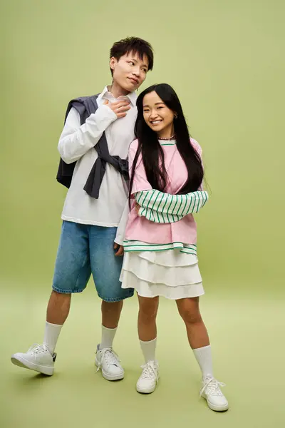 Stylish couple shares a joyful moment in vibrant outfits against a green backdrop. — Stock Photo