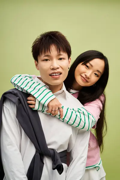 Couple embrasse ludique tout en mettant en valeur leurs tenues à la mode dans un cadre vert harmonieux. — Photo de stock