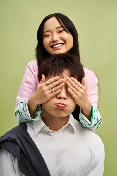 A joyful couple shares a playful moment, with her covering his eyes as he makes a funny face. — Stock Photo