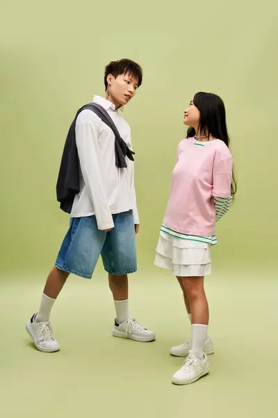 A stylish couple shares a playful gaze, showcasing their romance and trendy outfits. — Stock Photo